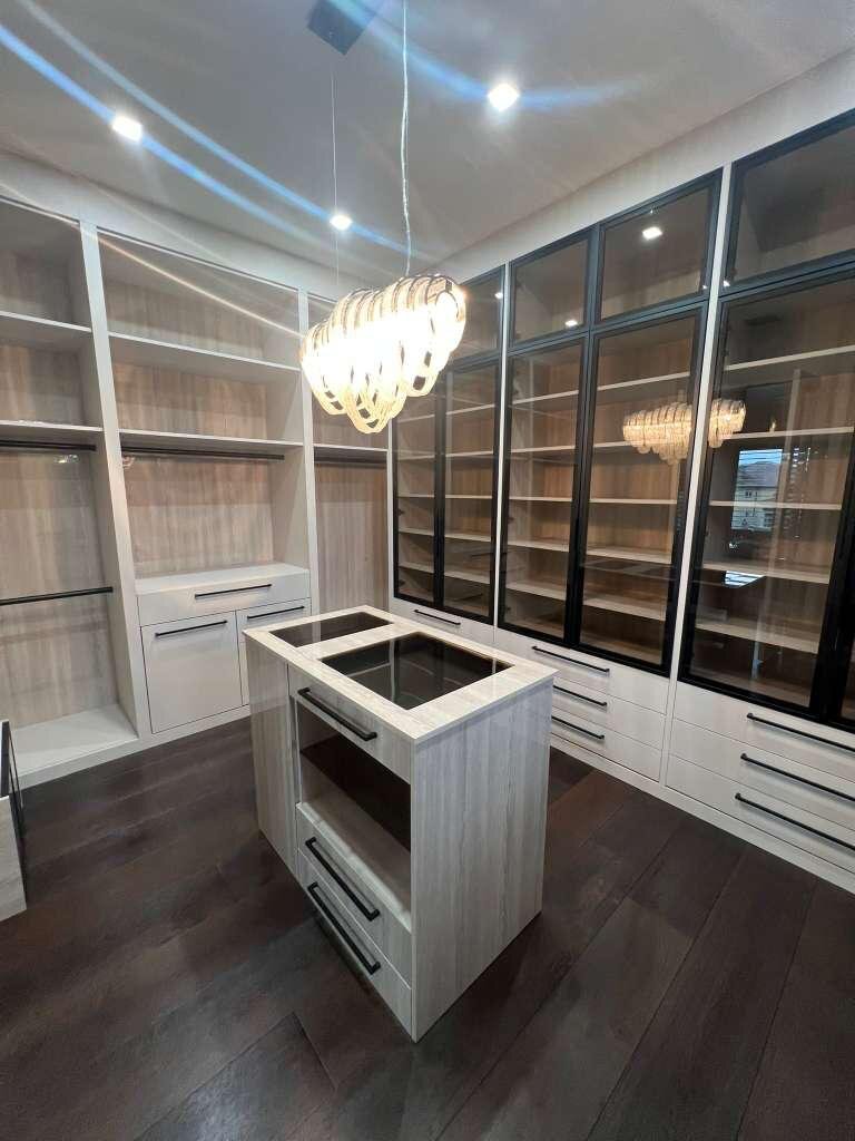 Luxury walk-in closet with center island and glass display cabinets